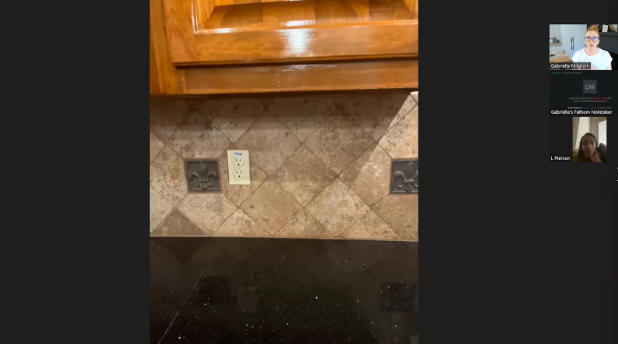 Kitchen counter with black granite surface and beige tiled backsplash, featuring two electrical outlets. Video call participants visible on the right.