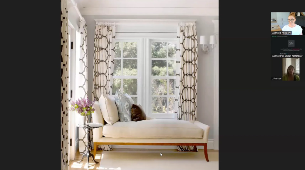 A cozy room with a beige chaise lounge by a window, patterned curtains, and a small side table with flowers. Soft natural light fills the space.